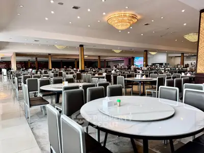 Spacious dining area with elegant chandeliers and modern seating, perfect for large gatherings or events.