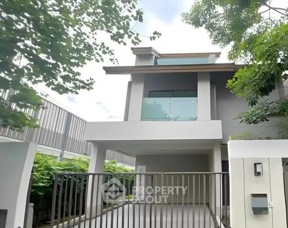 Modern two-story house with sleek balcony and gated driveway