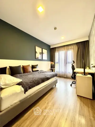 Modern bedroom with stylish decor and workspace, featuring large window and cozy ambiance.