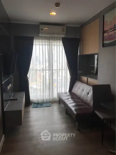 Modern living room with sleek furniture and large window offering natural light.