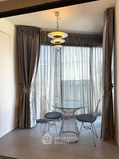 Chic dining nook with modern glass table and stylish chairs by large window, perfect for cozy meals.
