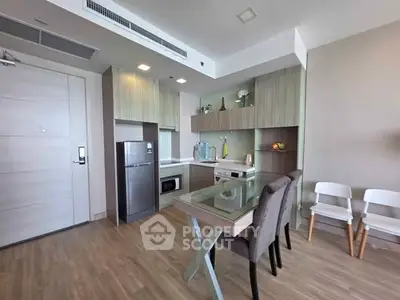 Modern kitchen with sleek cabinetry, stainless steel appliances, and dining area in a stylish apartment.