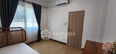 Cozy bedroom with natural light, wooden furniture, and air conditioning in a modern apartment.