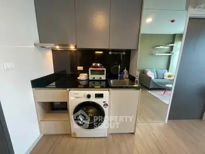 Modern compact kitchen with washing machine and open layout to cozy living room.