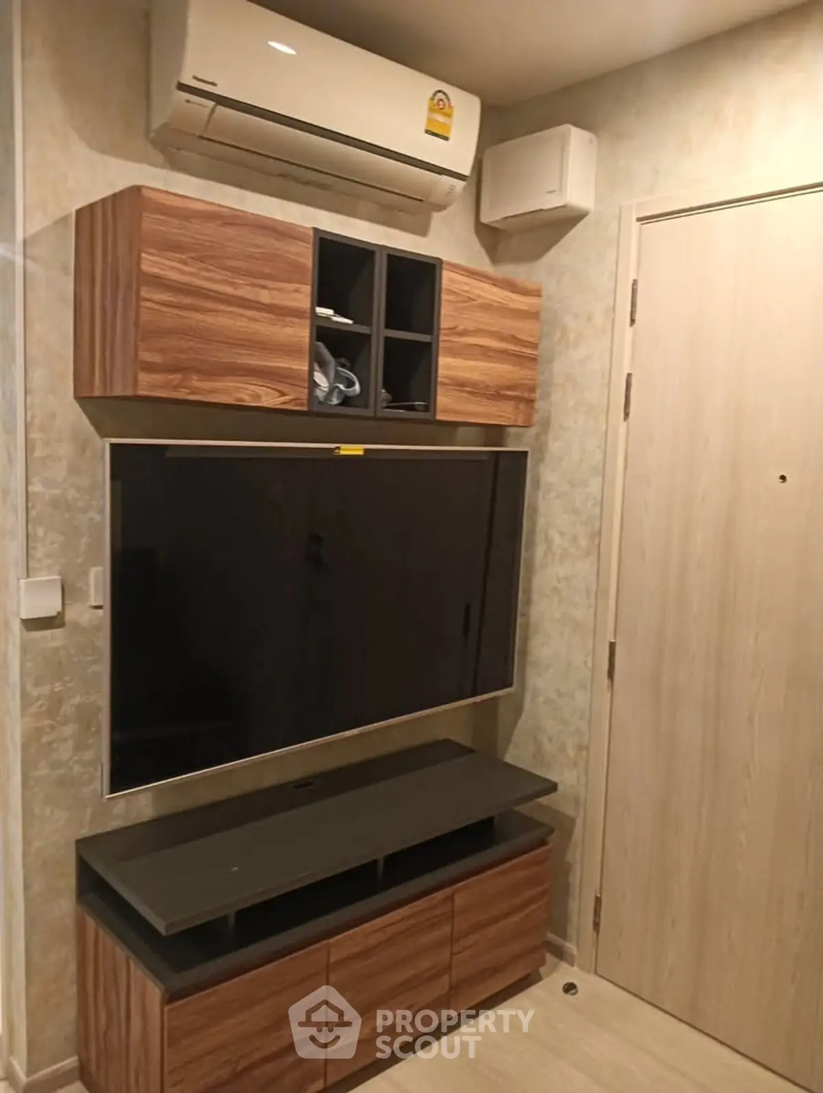 Modern living room with sleek wooden TV cabinet and wall-mounted air conditioner.