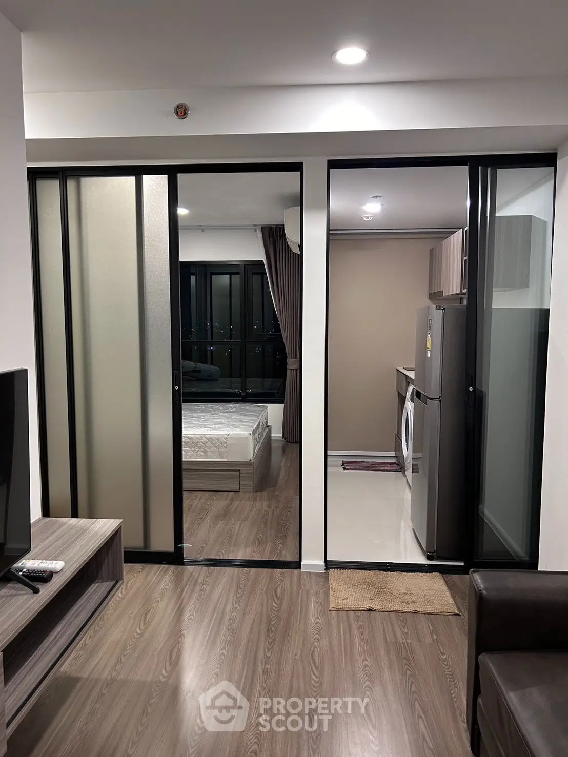 Modern apartment interior with sliding doors, featuring a cozy living area and a glimpse of the bedroom.