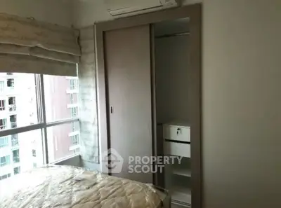 Cozy bedroom with built-in closet and large window in modern apartment