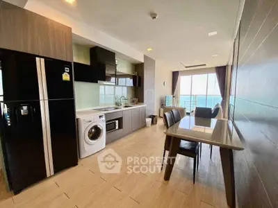 Modern kitchen with sleek appliances and dining area, featuring a washing machine and large fridge.