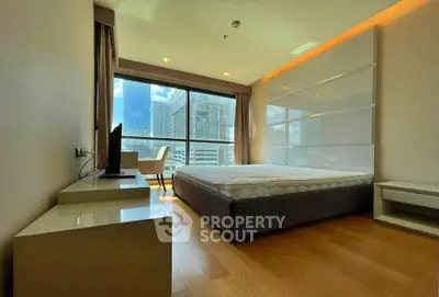 Modern bedroom with large window offering stunning city views and elegant furnishings.