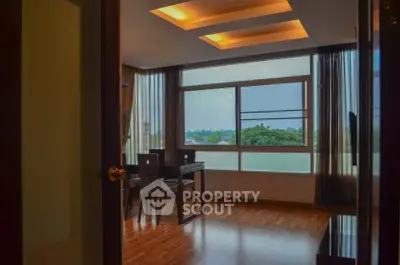Modern dining area with large windows and wooden flooring, offering a serene view.