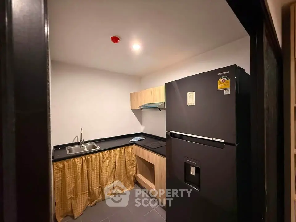 Cozy kitchen with modern fridge and compact layout, perfect for efficient cooking.