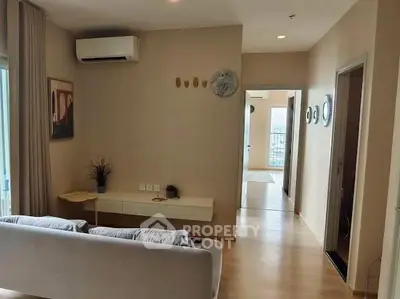 Modern living room with minimalist decor and air conditioning, featuring a cozy sofa and wall art.
