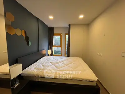 Modern bedroom with stylish decor and large window offering natural light.