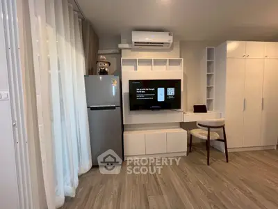 Modern living room with sleek furniture and built-in storage, featuring a wall-mounted TV and air conditioning.