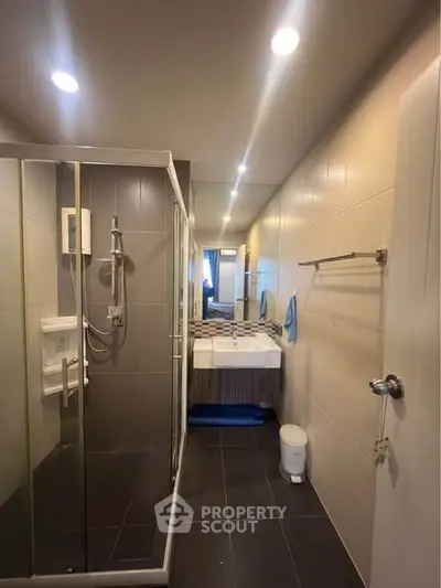 Modern bathroom with glass shower and sleek vanity in contemporary apartment.
