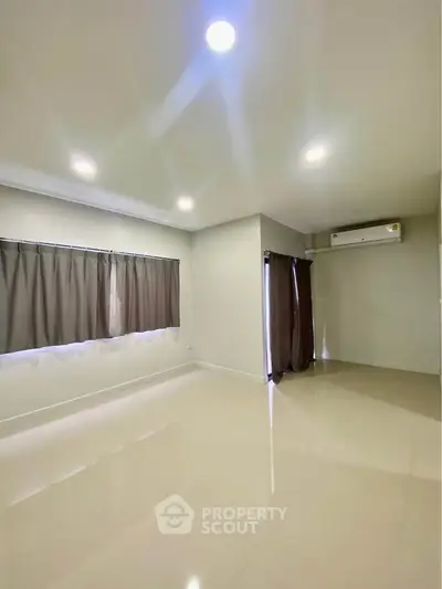 Spacious empty room with large windows and air conditioning, perfect for customization.