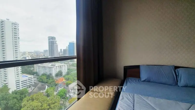 Spacious bedroom with stunning city view from large window in modern high-rise apartment.