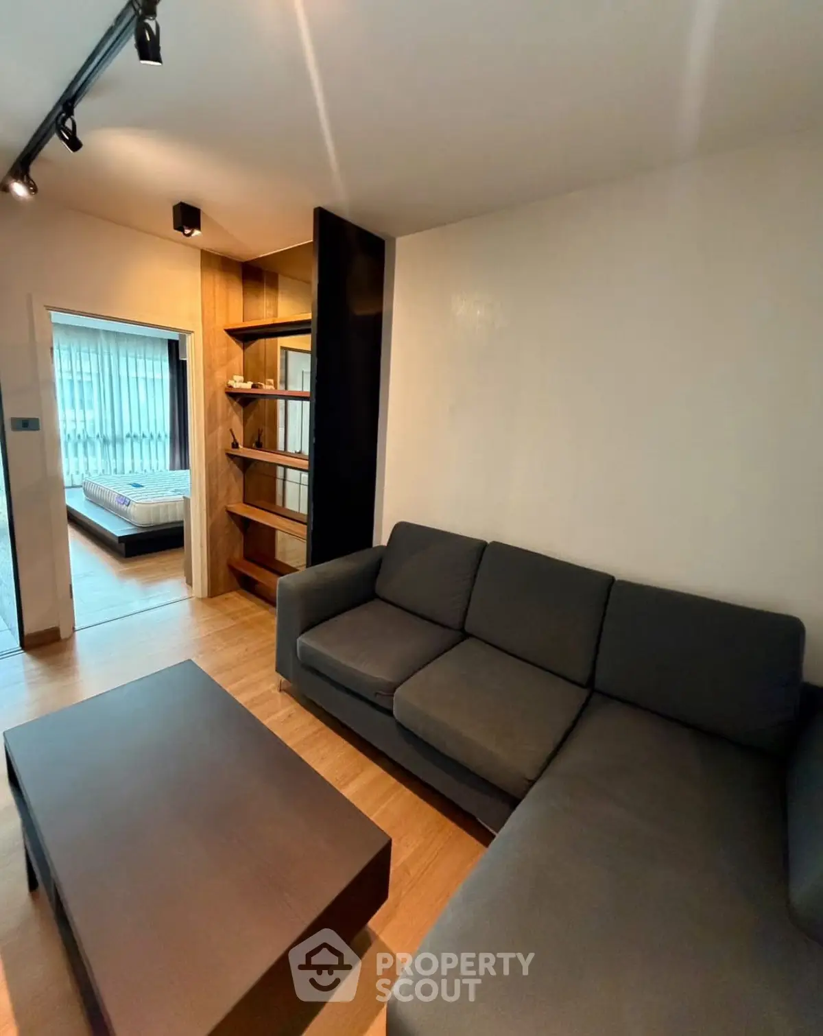 Modern living room with sleek furniture and open view to bedroom