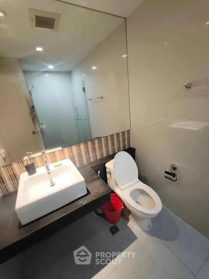 Modern bathroom with sleek design, featuring a large mirror, stylish sink, and contemporary fixtures.