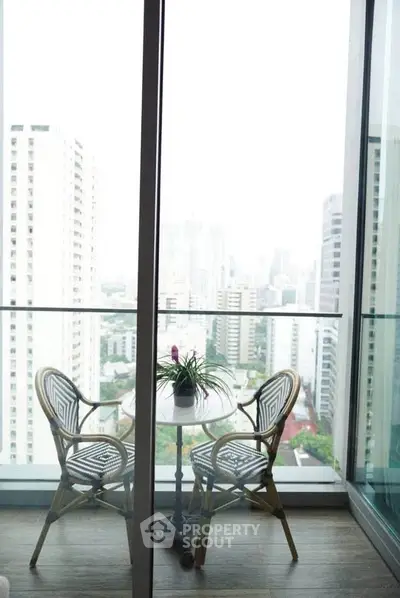 Chic balcony with city view, featuring stylish outdoor seating and glass railing for modern urban living.