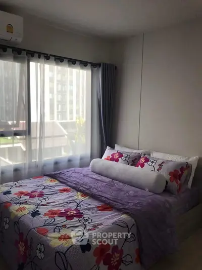 Cozy bedroom with floral bedding and large window offering natural light