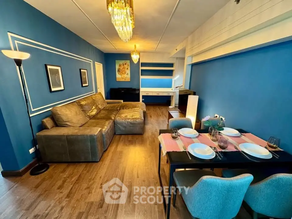 Chic living room with blue walls, elegant chandelier, and cozy dining area.