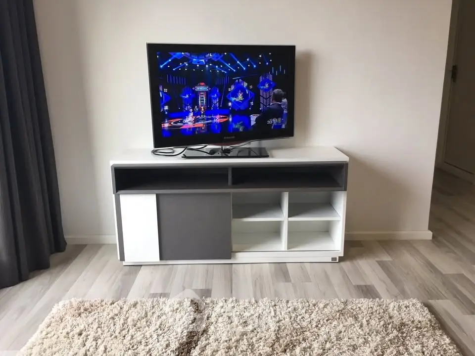 Modern living room with sleek TV stand and flat-screen TV on stylish wooden flooring.