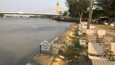 Riverside outdoor seating area with scenic bridge view and lush greenery