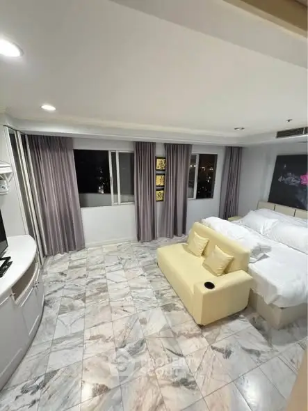 Spacious bedroom with marble flooring and cozy seating area, featuring large windows with city views.
