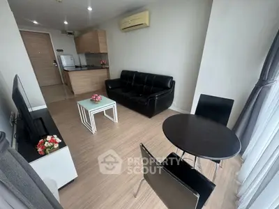 Modern living room with sleek black furniture and open kitchen layout