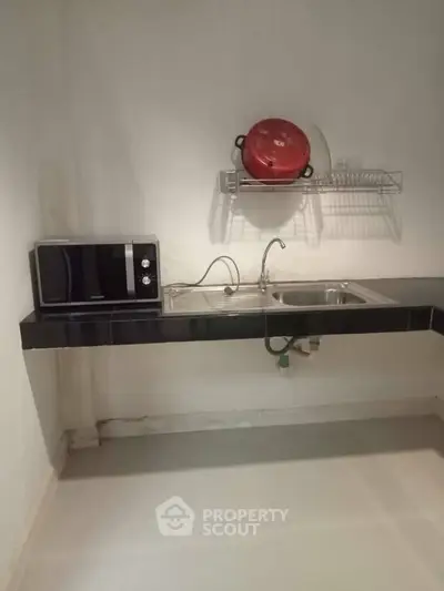 Compact kitchen with microwave and sink, ideal for efficient cooking in small spaces.