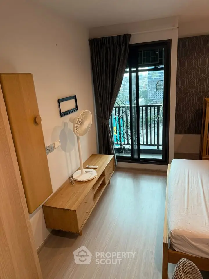 Modern bedroom with balcony view, featuring wooden furniture and stylish decor.