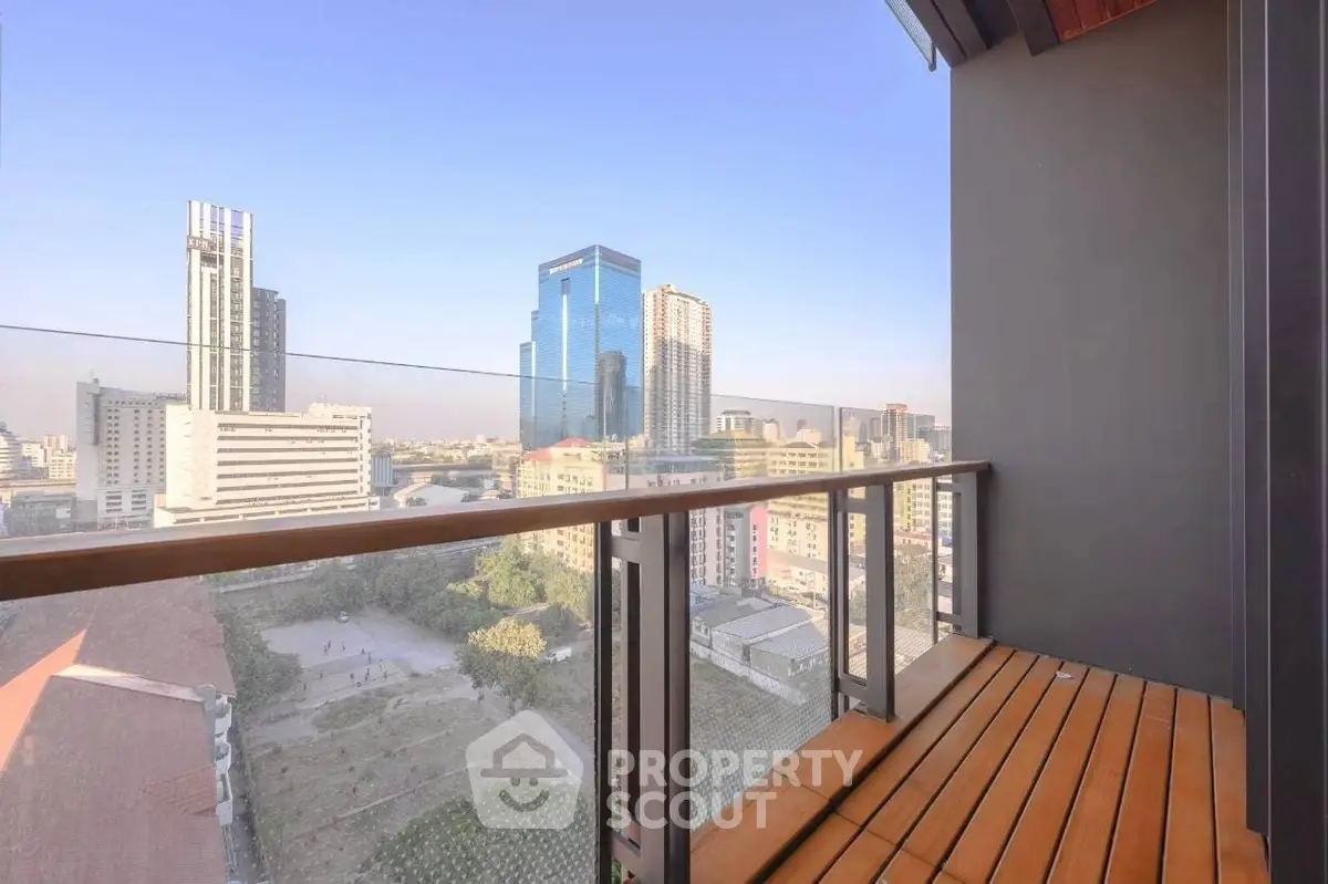 Stunning cityscape view from a modern balcony with sleek glass railing and wooden flooring.