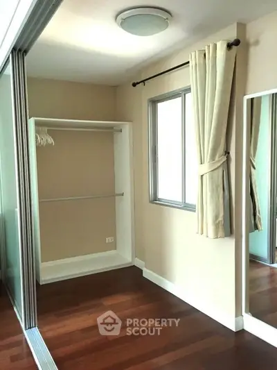 Spacious walk-in closet with wooden flooring and natural light.