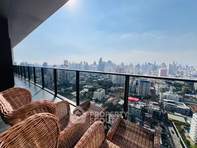Stunning cityscape view from a high-rise balcony with wicker furniture