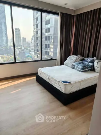 Modern bedroom with city view and large windows in high-rise apartment