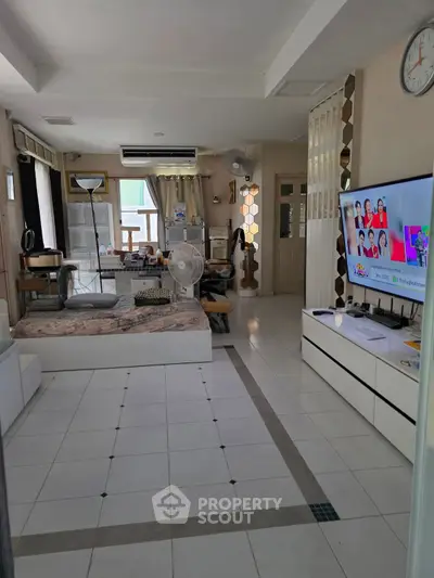 Spacious living room with modern decor and large TV, perfect for relaxation.