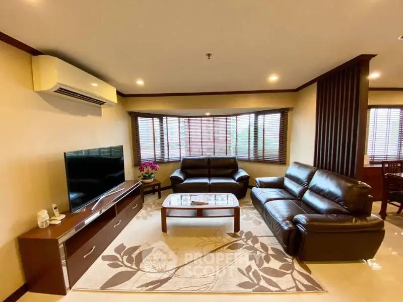 Spacious living room with leather sofas and modern decor in a cozy apartment.