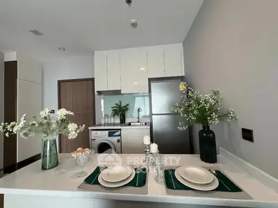 Modern kitchen with open layout, featuring stainless steel appliances, white cabinetry, and a neatly set dining counter.