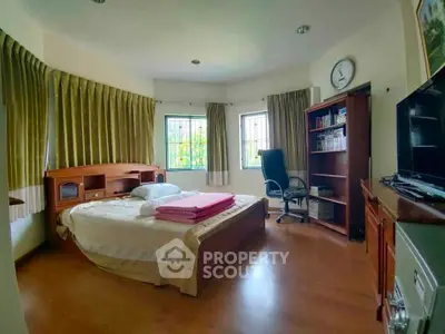 Spacious bedroom with wooden furniture and large windows for natural light.