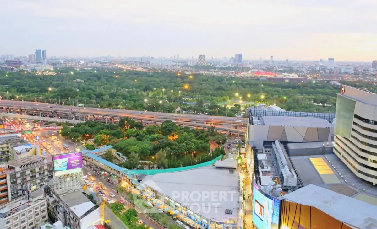 Stunning cityscape view from high-rise building overlooking lush green park and bustling city streets.