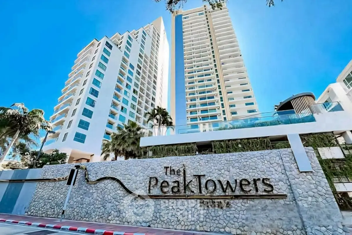 Stunning view of modern high-rise Peak Towers with lush greenery and blue sky backdrop.