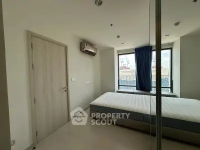 Spacious bedroom with large window and air conditioning in modern apartment.