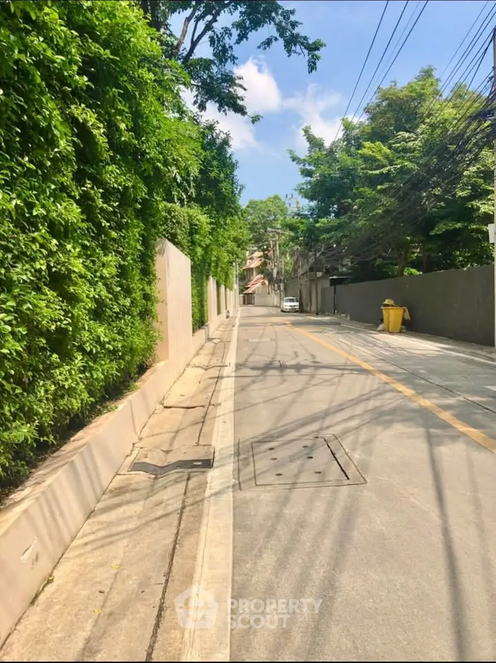 Charming residential street with lush greenery and clear blue sky, perfect for serene living.