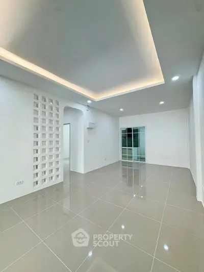 Spacious modern living room with sleek tile flooring and ambient ceiling lighting
