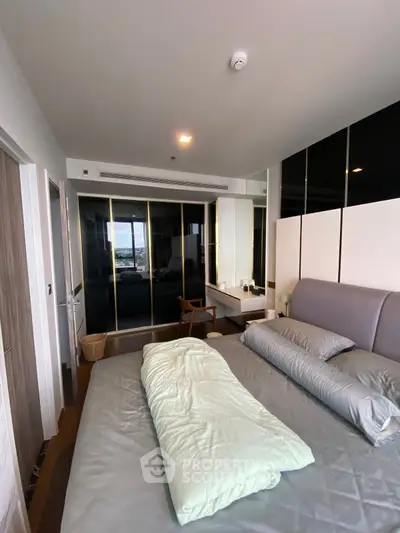 Modern bedroom with sleek design, featuring a large bed, mirrored wardrobe, and stylish decor.