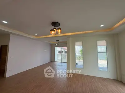 Spacious living room with modern lighting and large windows offering natural light.