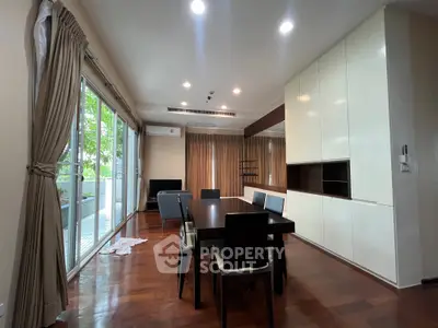 Spacious living room with elegant dining area and large windows opening to a balcony.