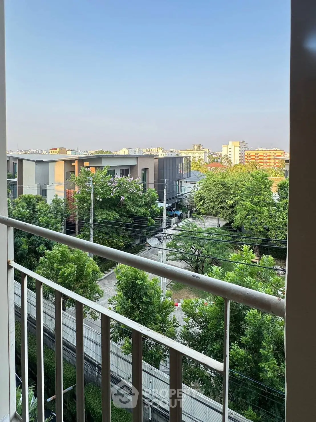 Stunning balcony view overlooking lush greenery and modern buildings, perfect for urban living.