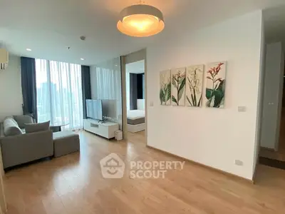Modern living room with wooden flooring and natural light, featuring a cozy sofa and stylish decor.